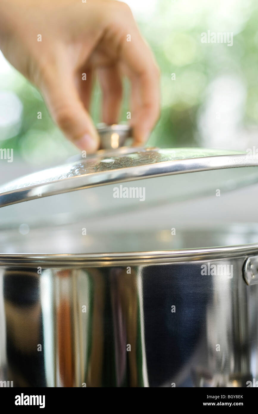 Person removing lid from cooking pot Stock Photo Alamy