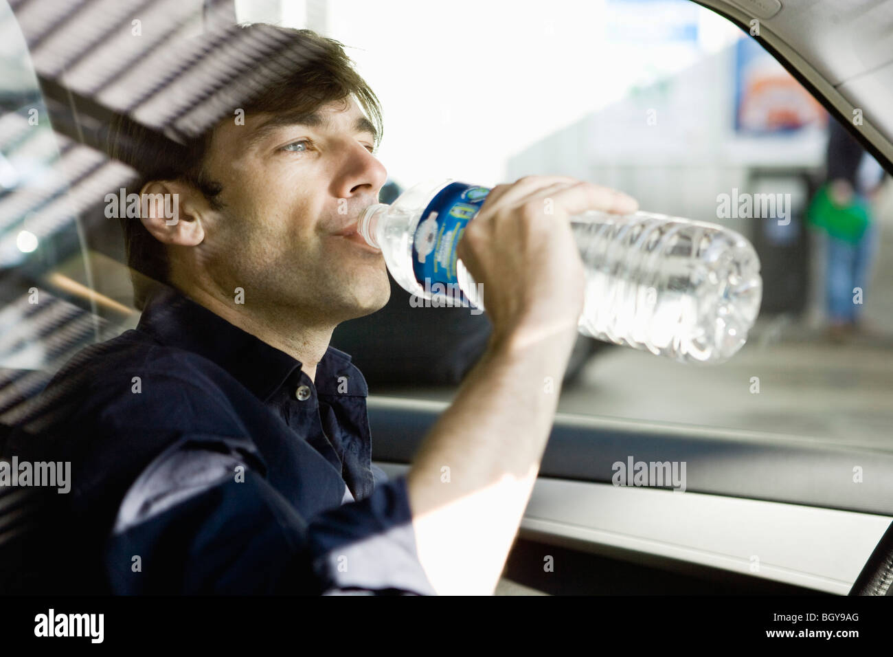 Man drinking bottled water while driving Stock Photo