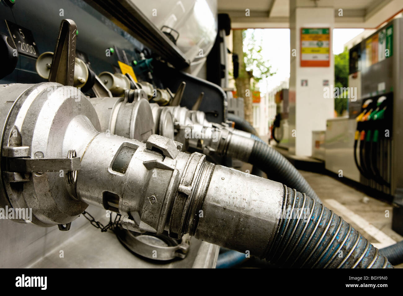 Hoses connected to fuel tanker outlets transferring fuel to gas station