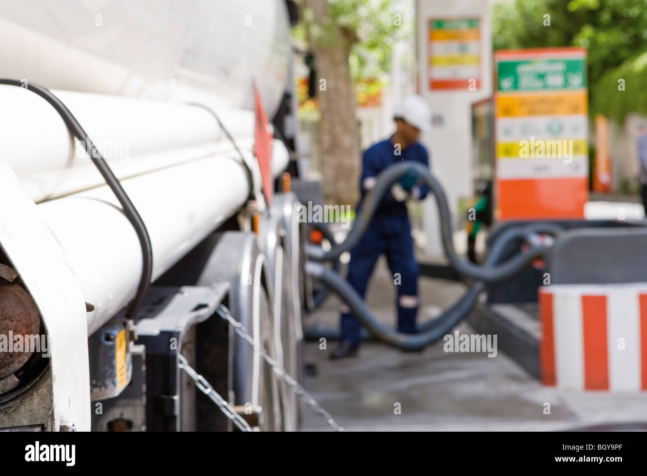 Hoses connected to fuel tanker outlets transferring fuel to gas station