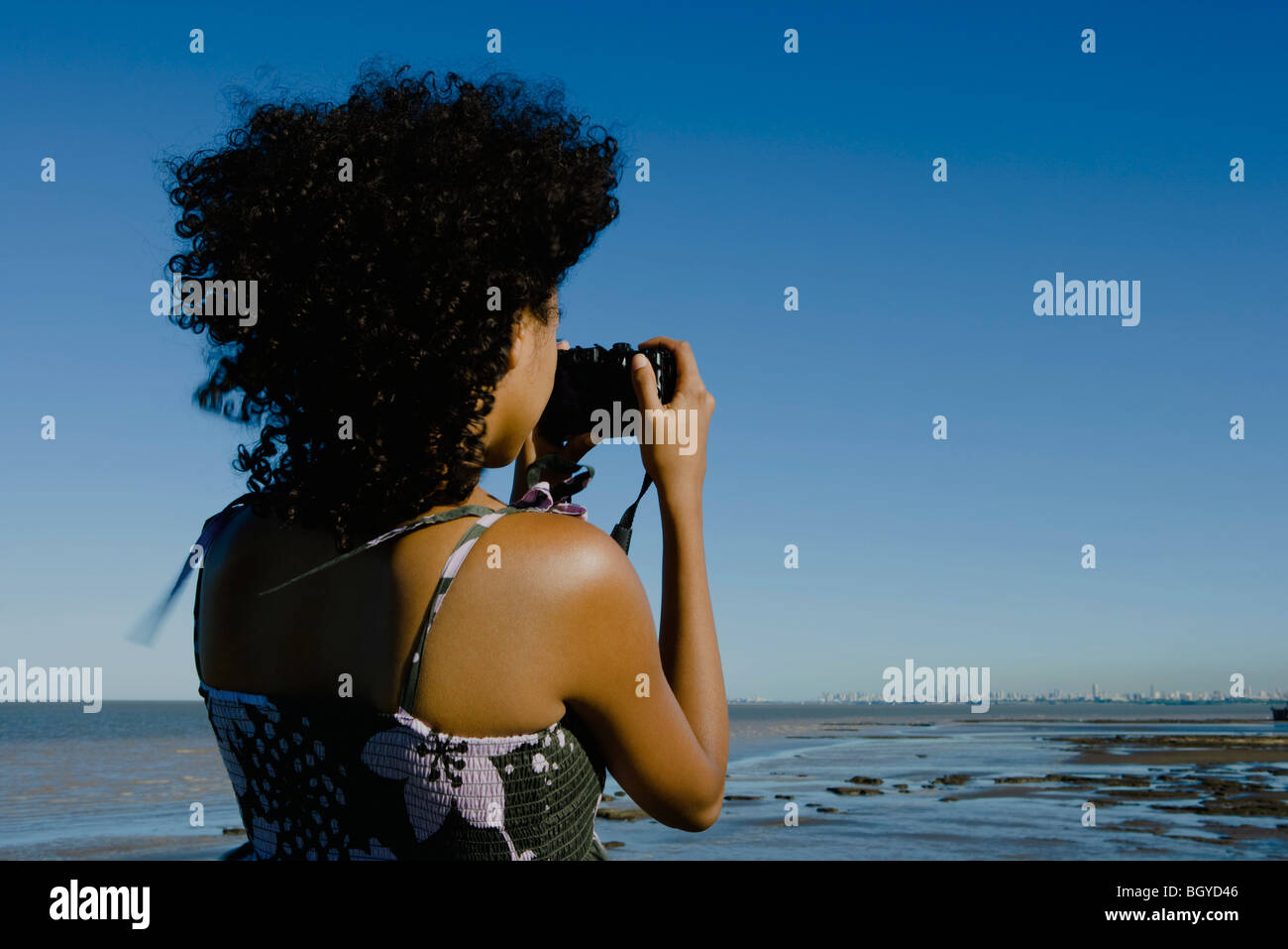 Young woman photographing coast with camera, rear view Stock Photo - Alamy