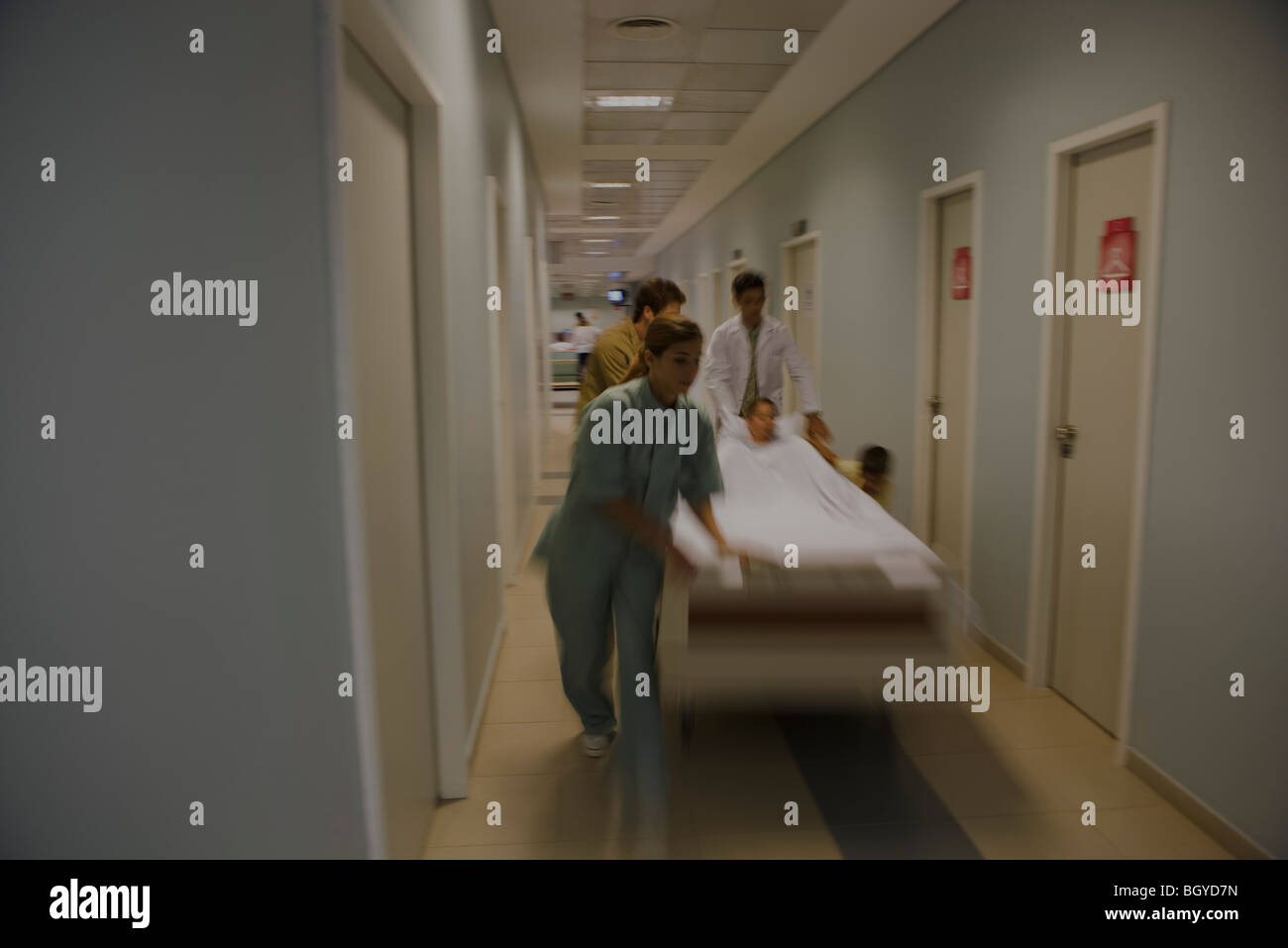 Healthcare workers running with patient on gurney in hospital corridor Stock Photo