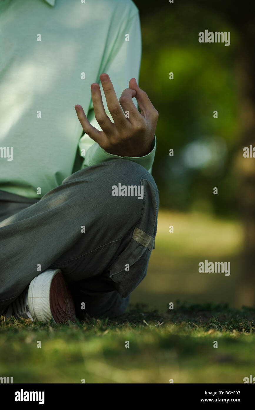 Man sitting on grass in lotus position, cropped Stock Photo
