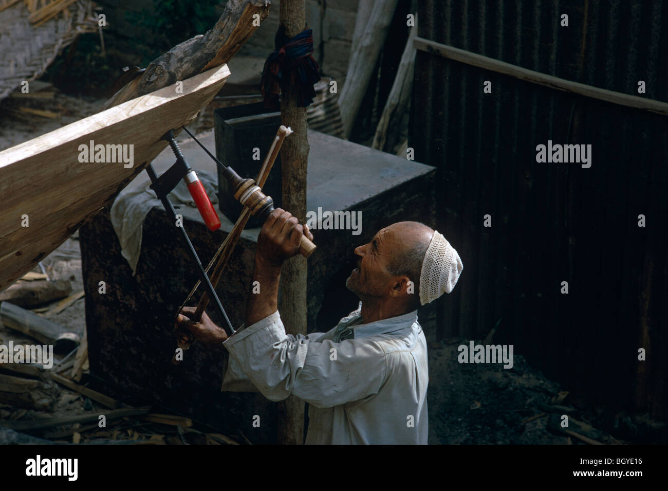 Traditional boatbuilder drilling with old-fashioned tools in Kuwait. He is working on a dhow. Stock Photo