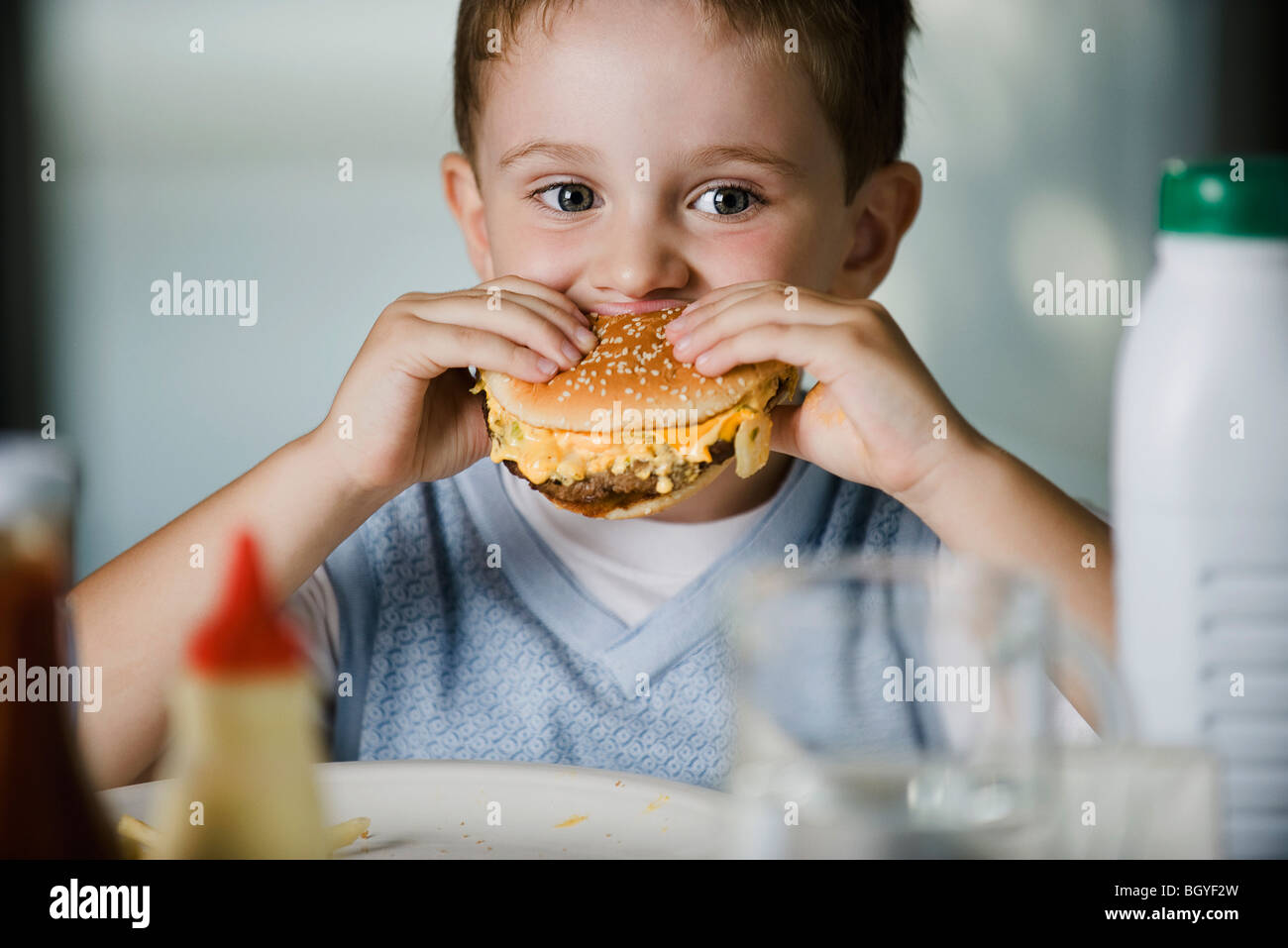 Little boy eating cheeseburger Stock Photo Alamy