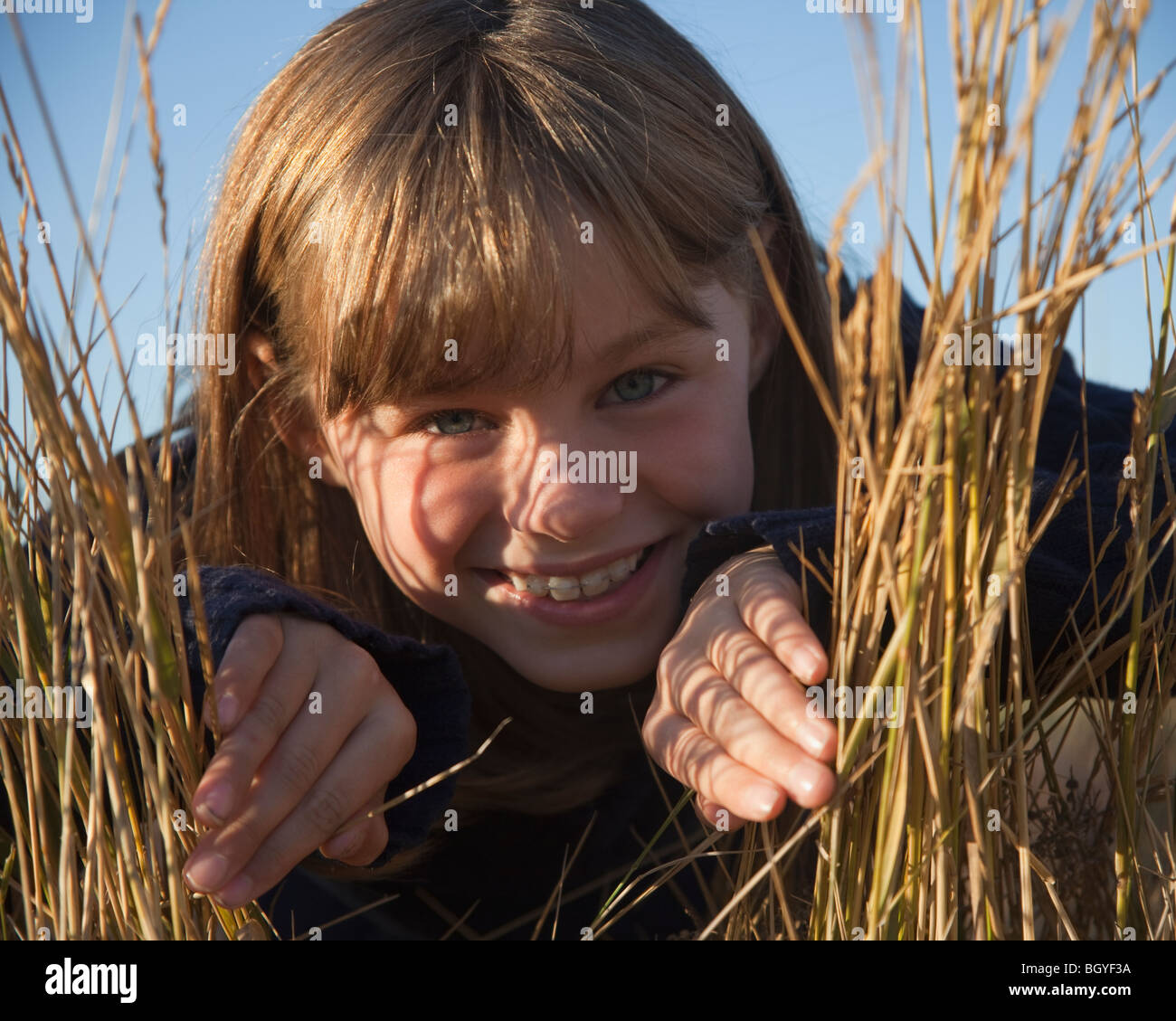 Young girl peaking out from behind grass Stock Photo Alamy