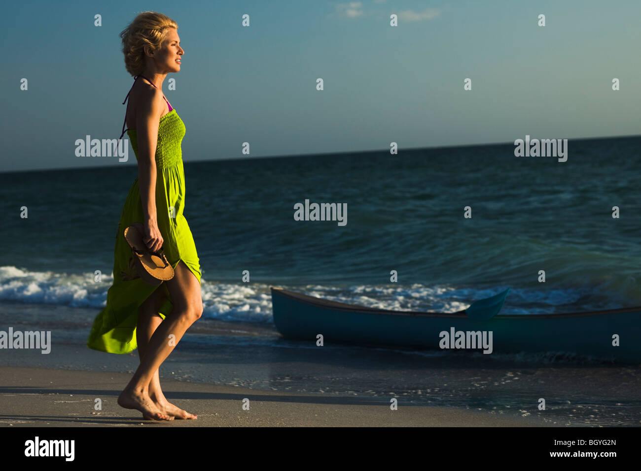 Woman in sundress walking on beach, looking at sea Stock Photo - Alamy