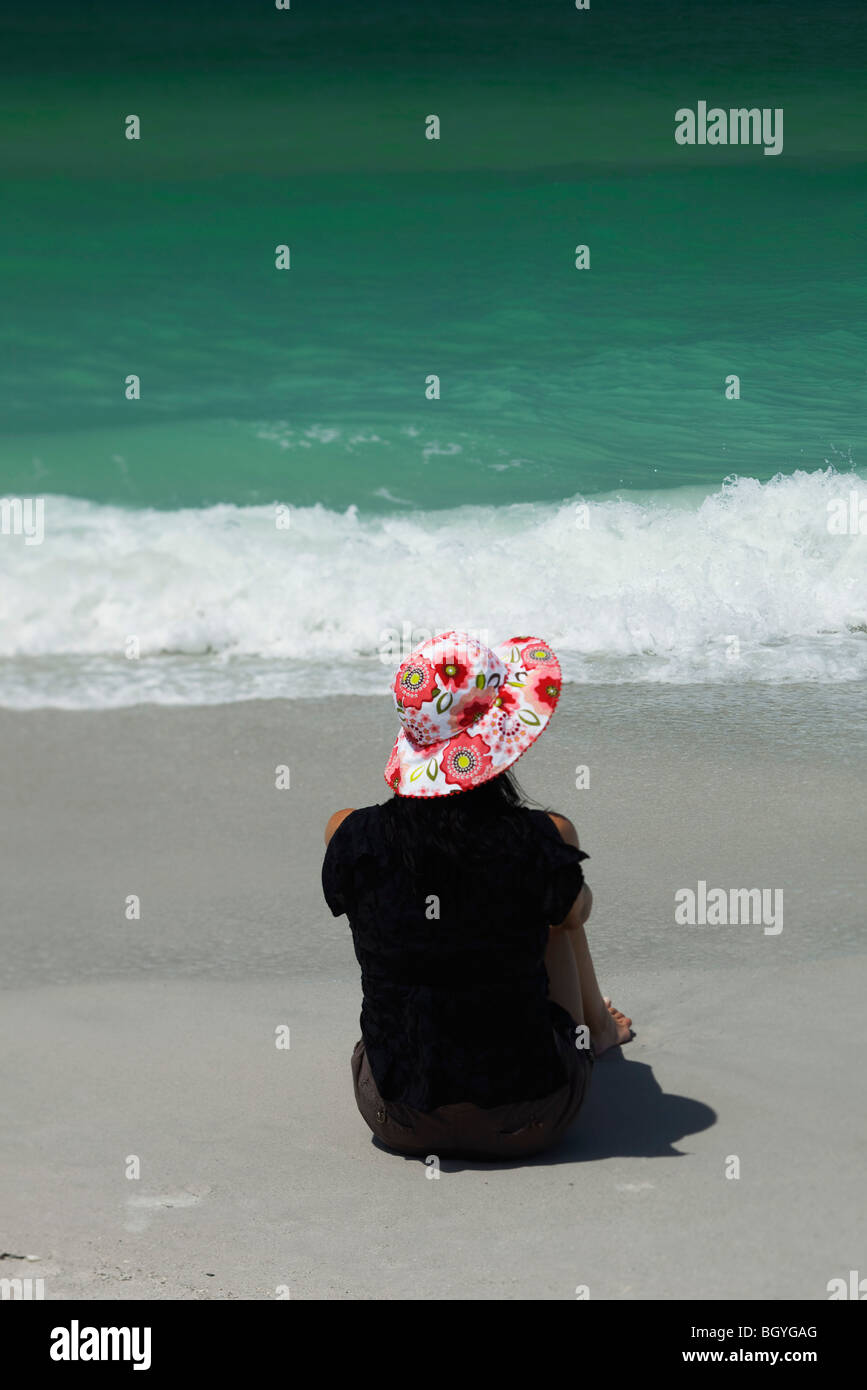 Woman sitting on beach looking at sea, rear view Stock Photo - Alamy