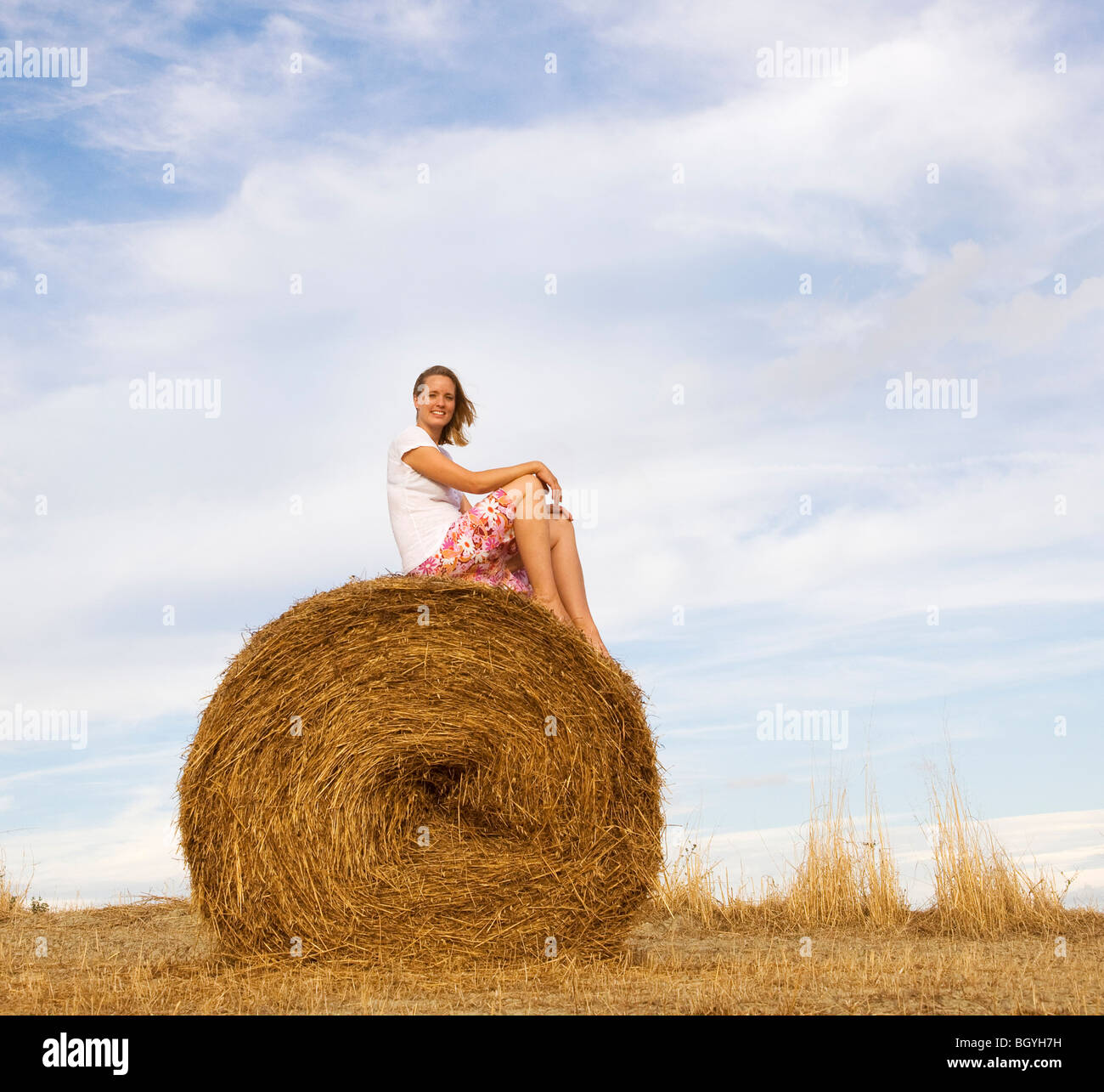 woman sitting on hay bale Stock Photo