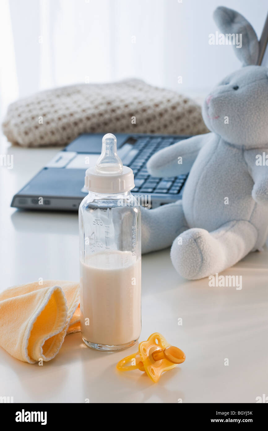 Baby bottle beside laptop Stock Photo