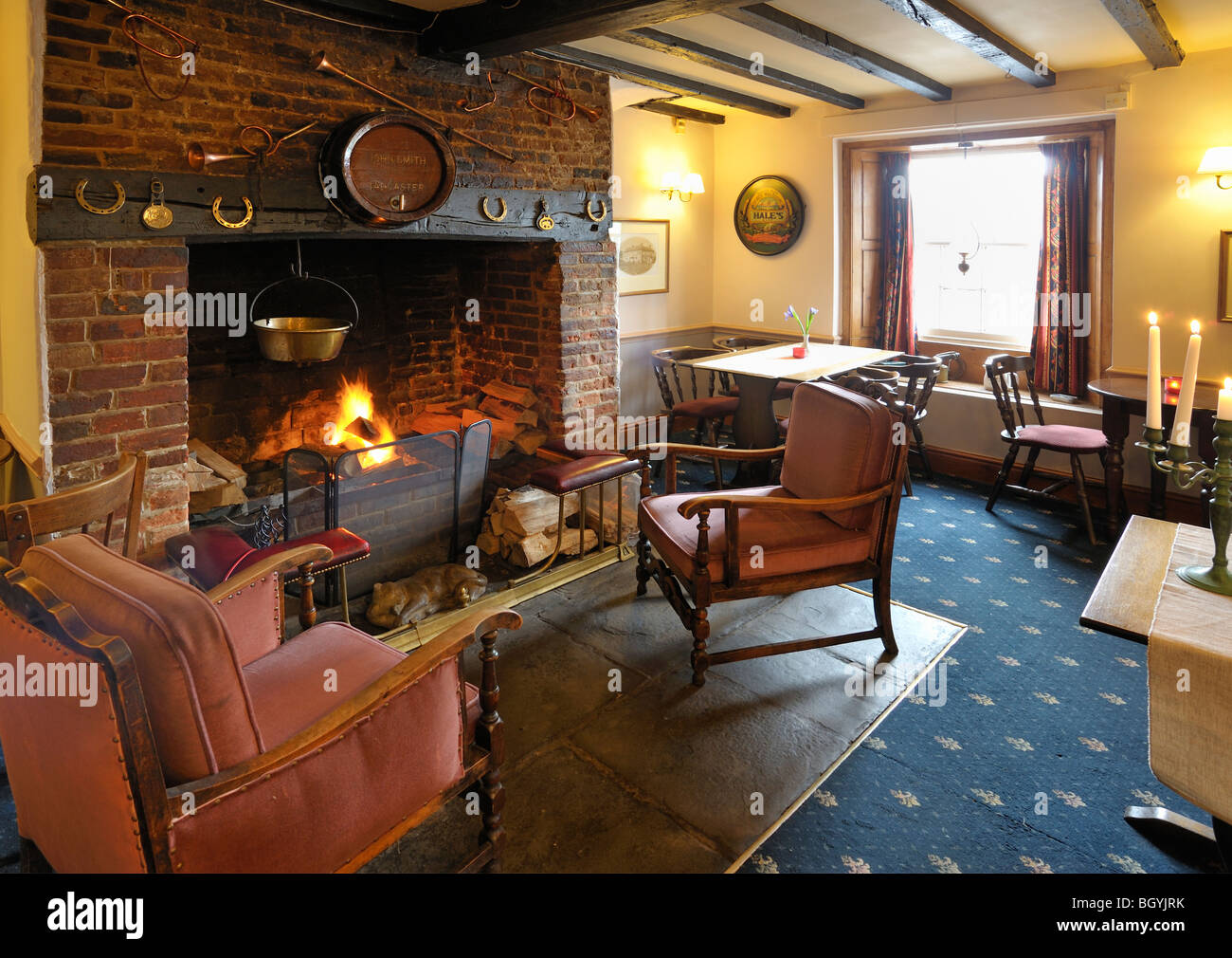 A large log fire forms a cosy centerpiece to the inside of a pub Stock Photo