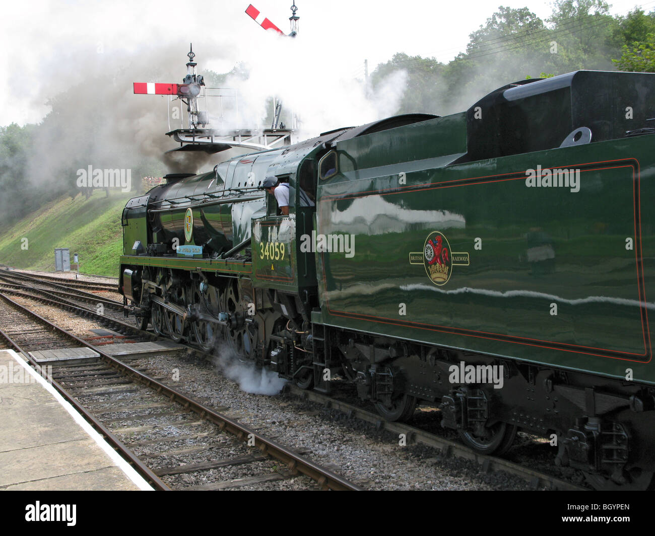 Steam Loco at Bluebell Heritage railway pulling out of station in front of signals with plenty of steam Stock Photo