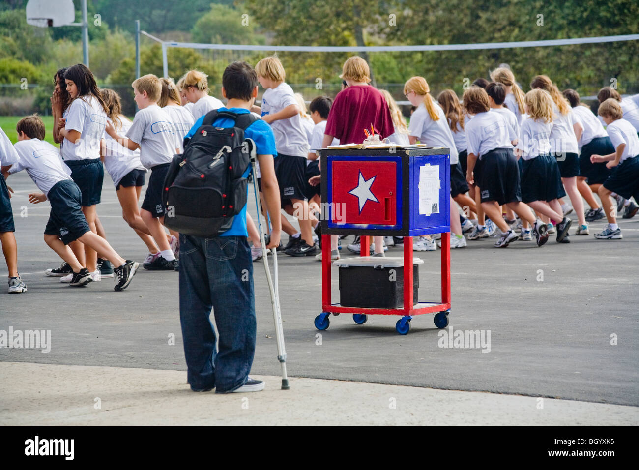 On crutches and unable to participate, a handicapped California middle school student watches a campus physical education class. Stock Photo