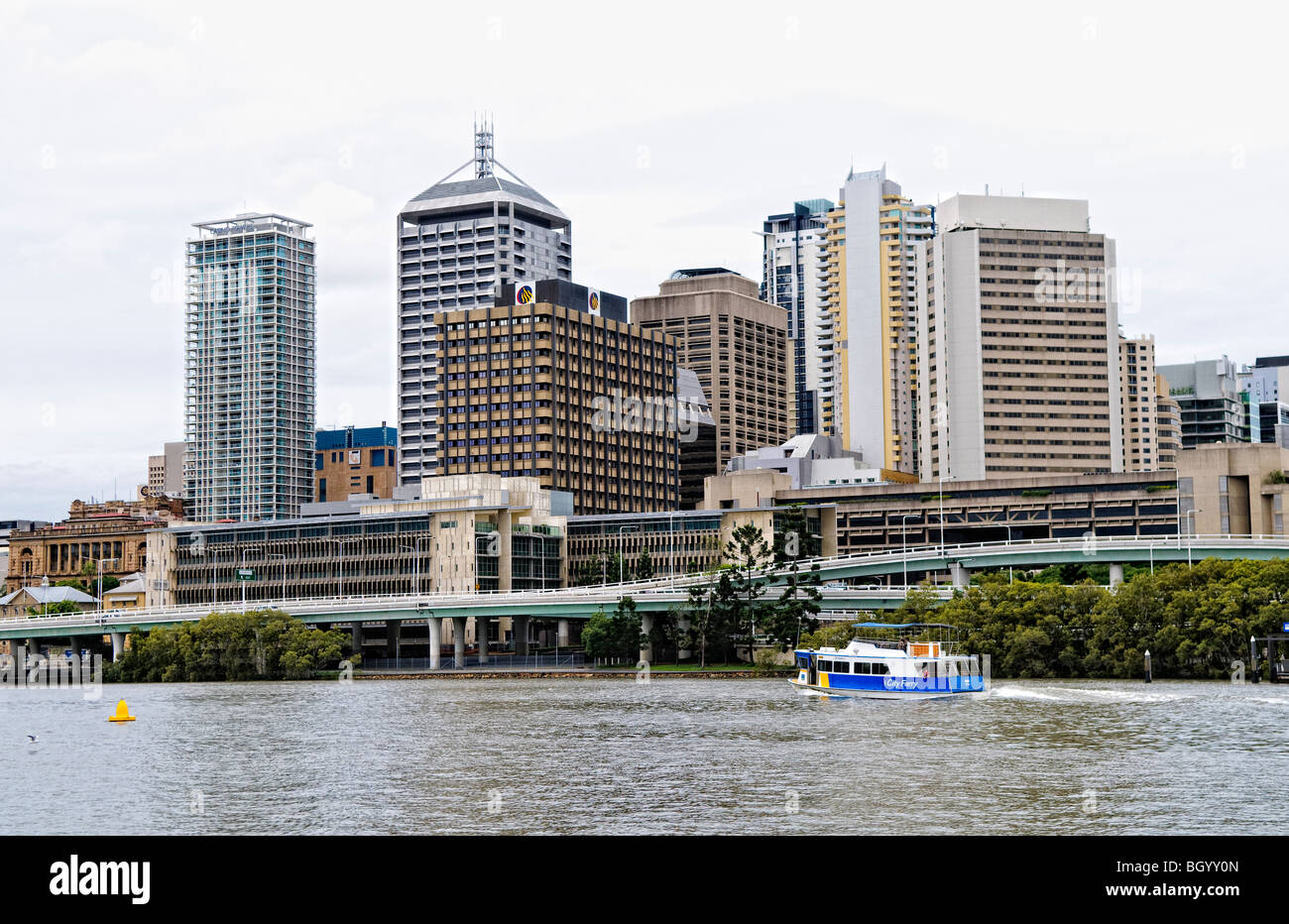 Brisbane River City Skyline Southbank Brisbane Australia // BRISBANE, Australia — The Brisbane River flows past the city skyline as viewed from Southbank, with the Southeast Freeway (Pacific Motorway) running along the waterfront. Brisbane, the capital of Queensland, features a mix of modern skyscrapers and public spaces along its winding river. The Southbank Parklands area, developed on the site of World Expo '88, offers recreational spaces and cultural venues opposite the central business district. Stock Photo