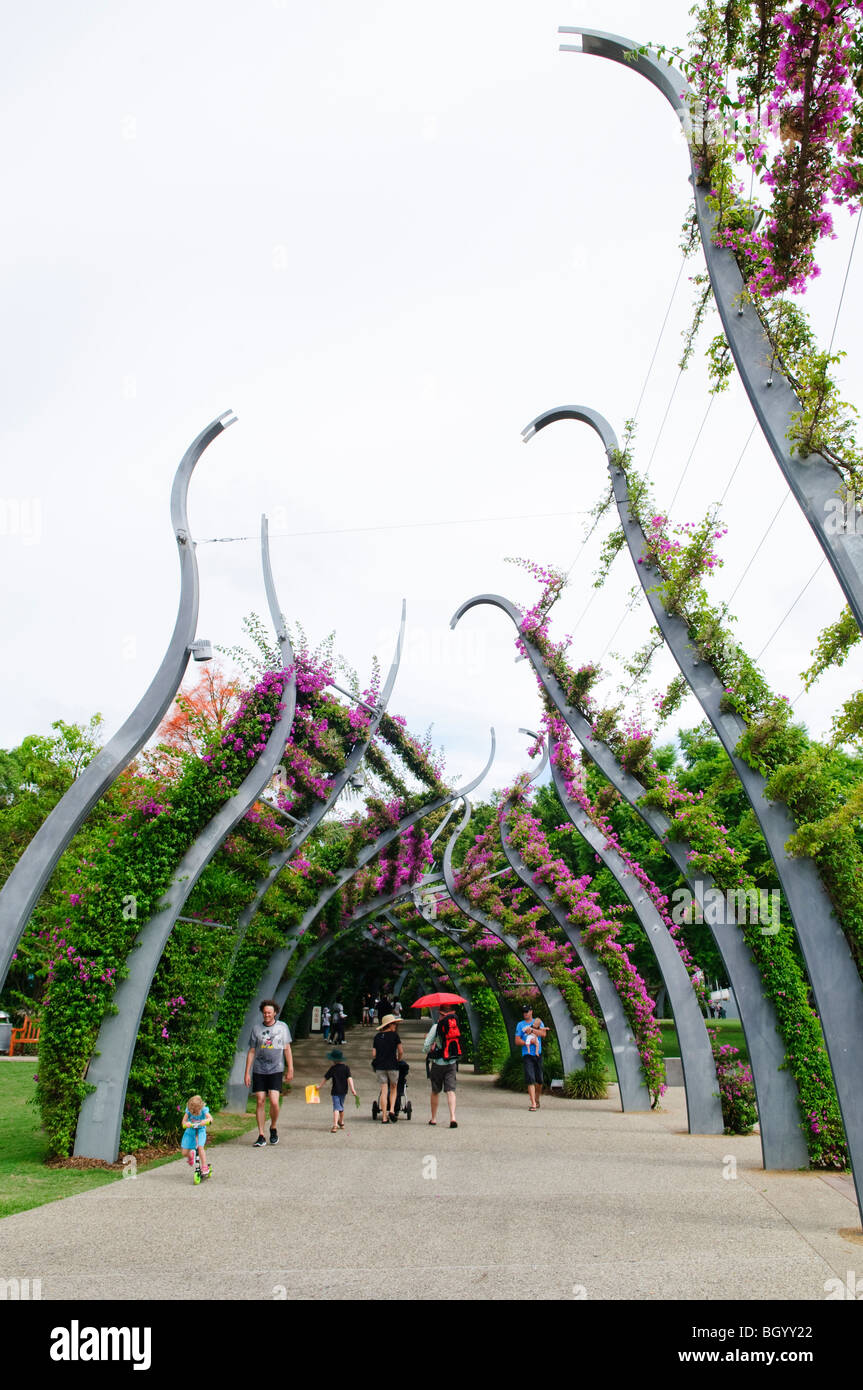 South Bank Parklands Walkway Arches Brisbane Australia // BRISBANE, Australia — Artistically styled walkway arches in Brisbane's South Bank Parklands are covered in flowering vines, creating a shaded pedestrian corridor. The parklands, situated along the southern banks of the Brisbane River, were developed on the site of World Expo '88 and have become one of the city's premier recreational areas. This verdant urban space features gardens, restaurants, and cultural venues, serving as a popular gathering spot for both locals and tourists in Queensland's capital city. Stock Photo