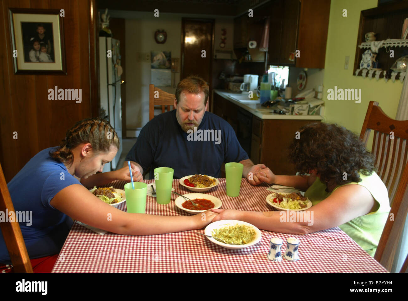 Carrie Lynn Peace, Scott Peace and Rachel Peace pray before dinner. Scott Peace is the youth pastor at the Southside Christian C Stock Photo