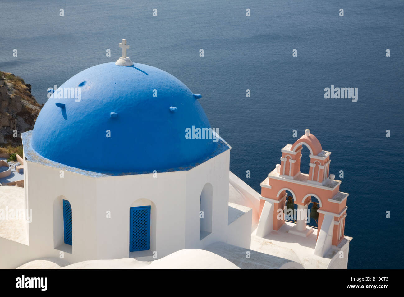 Blue domed church and bell tower in a village overlooking Santorini's lagoon, Oia, Greece Stock Photo