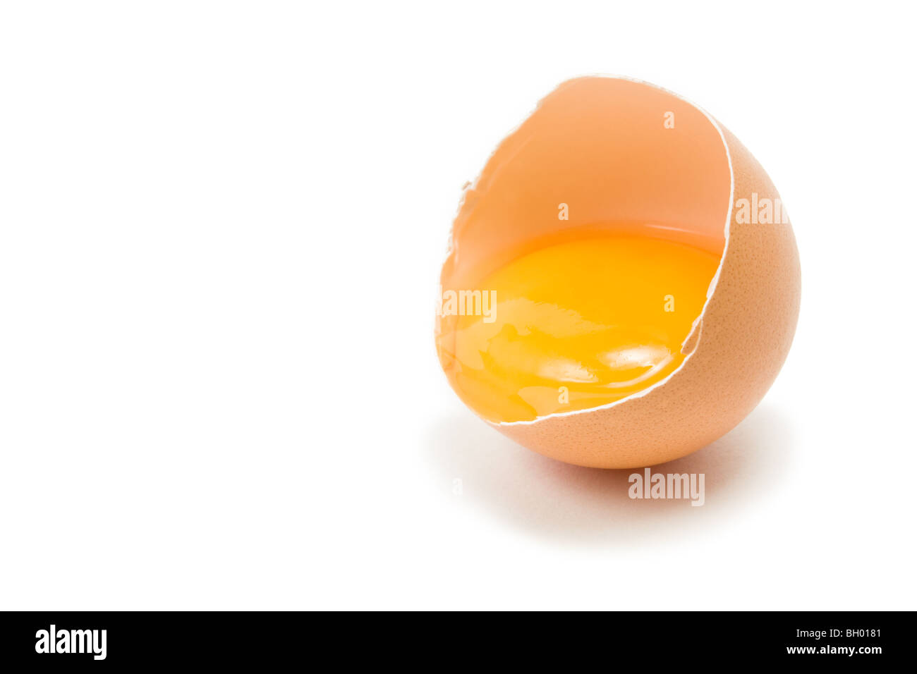 Single cracked open Hens Egg showing yolk isolated against white background Stock Photo
