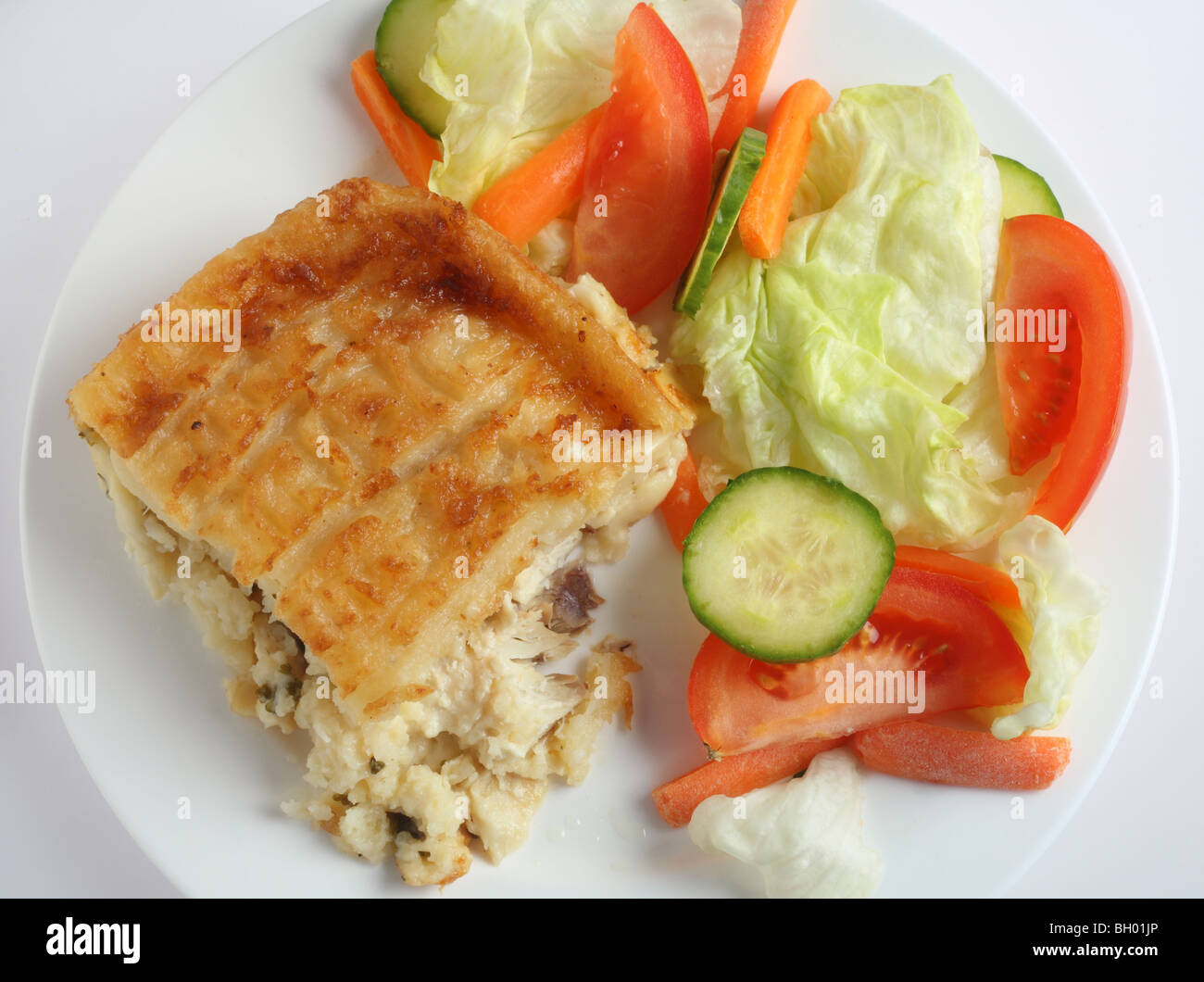 Traditional seafood pie, with fish in bechamel sauce topped with mashed potato and baked, served with a salad, high angle view Stock Photo