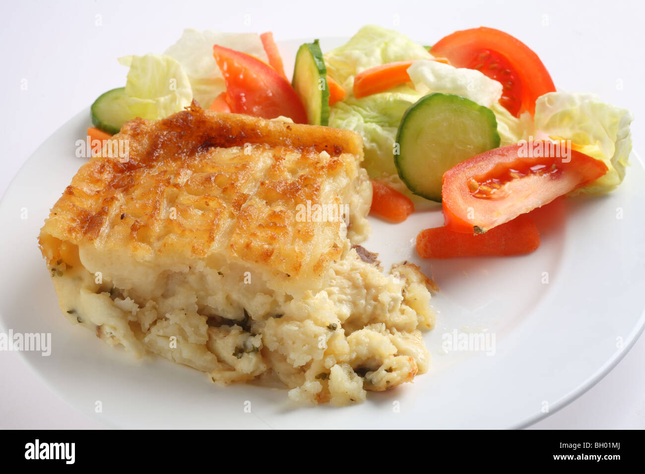 Traditional seafood pie, with fish in bechamel sauce topped with mashed potato and baked, served with a salad, side view Stock Photo