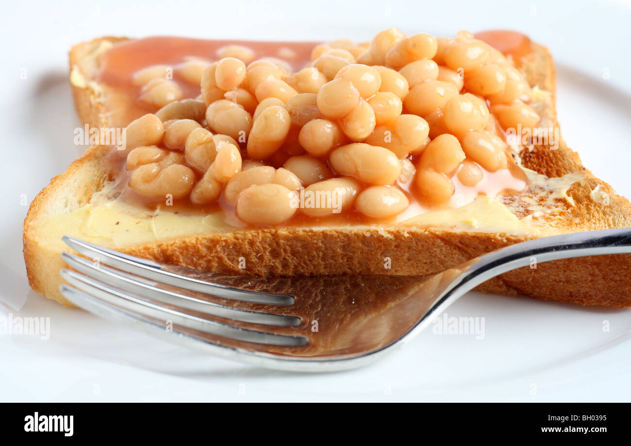 Extreme close-up on a plate of beans on toast with a fork. Stock Photo
