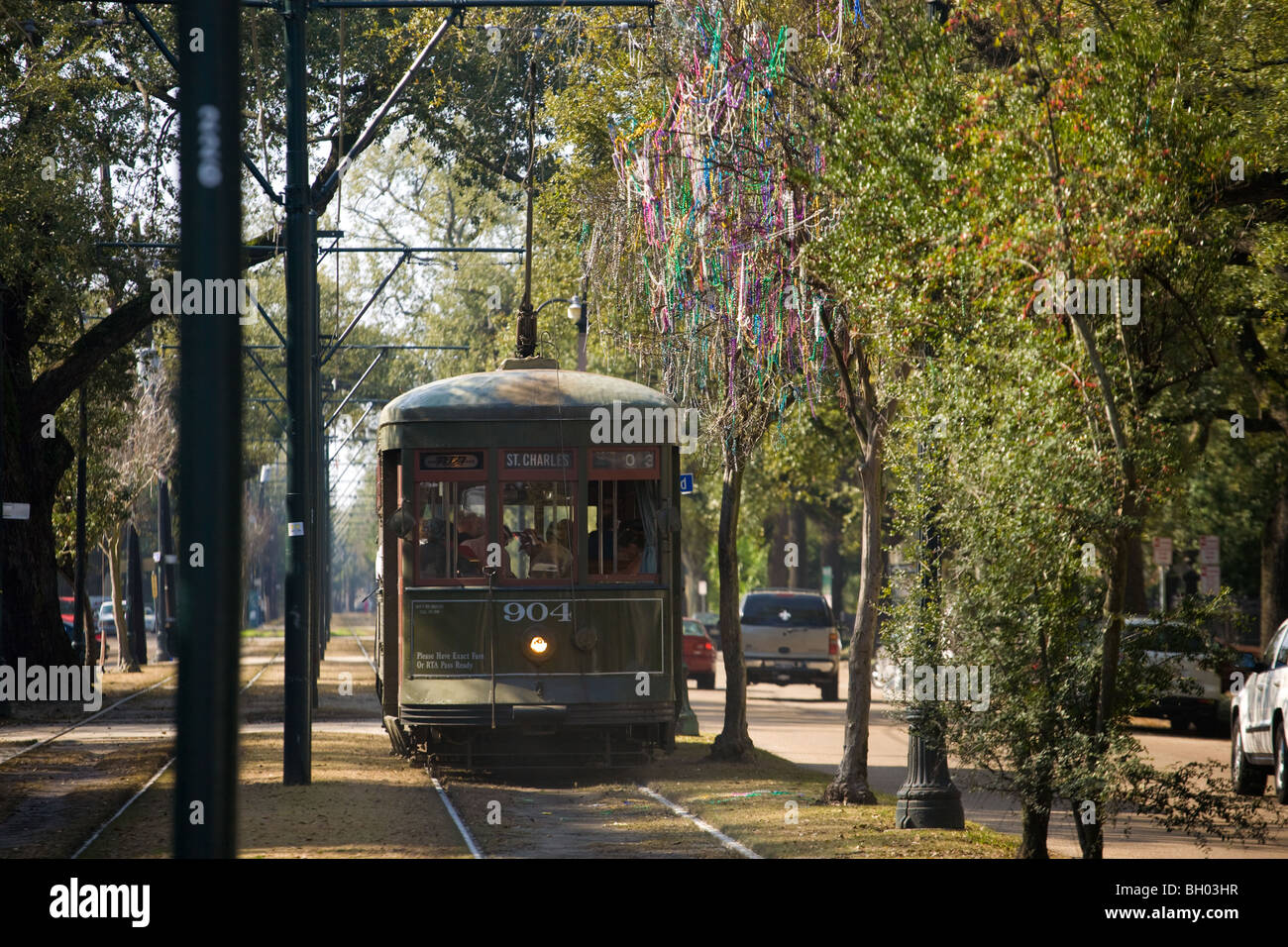 St. Charles Streetcar passing under beads hung tree, Garden District, New Orleans, Louisiana Stock Photo