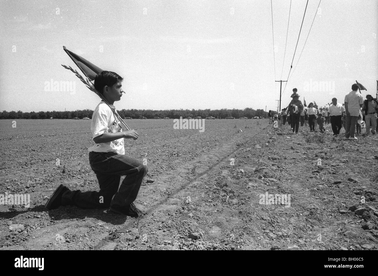 A mexican-american boy with flags in an empty field after Cesar Chavez' funeral; Delano, California, 1993. United Farmworkers Stock Photo