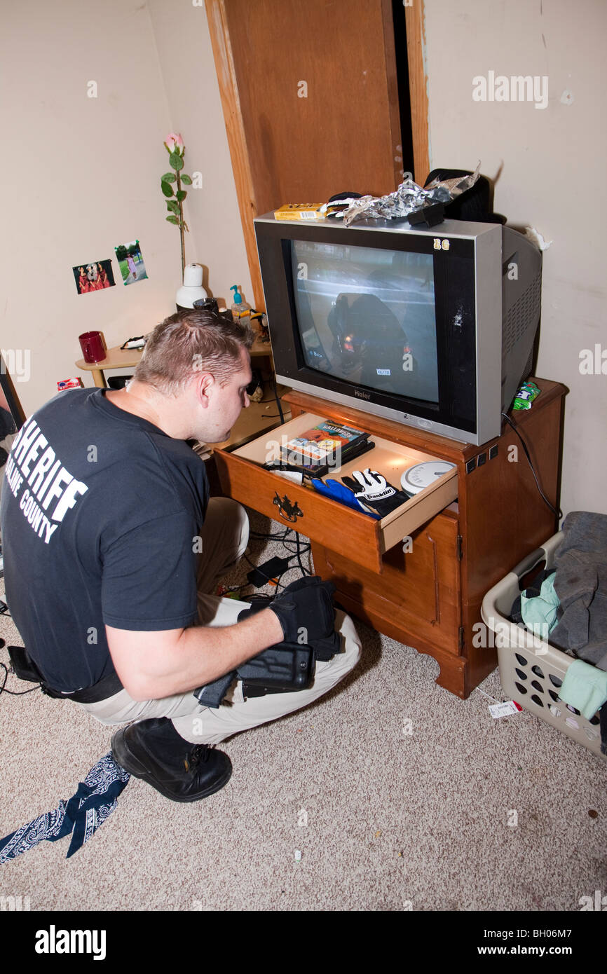 Deputy sheriff searching drawer during drug raid. Stock Photo