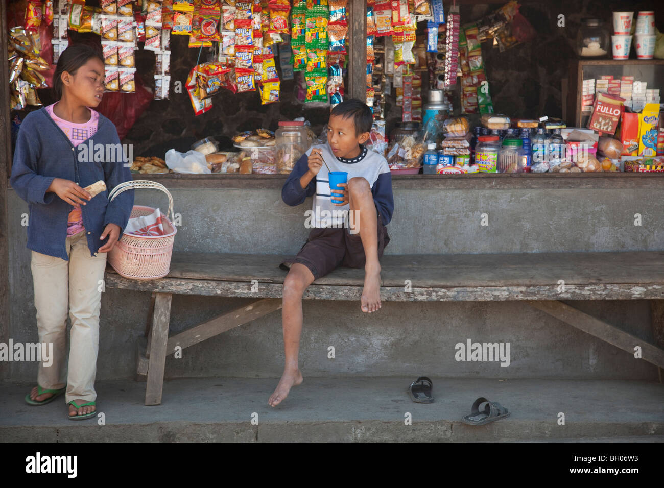 A Bali open market provisions shop with two young people buying goods Stock Photo