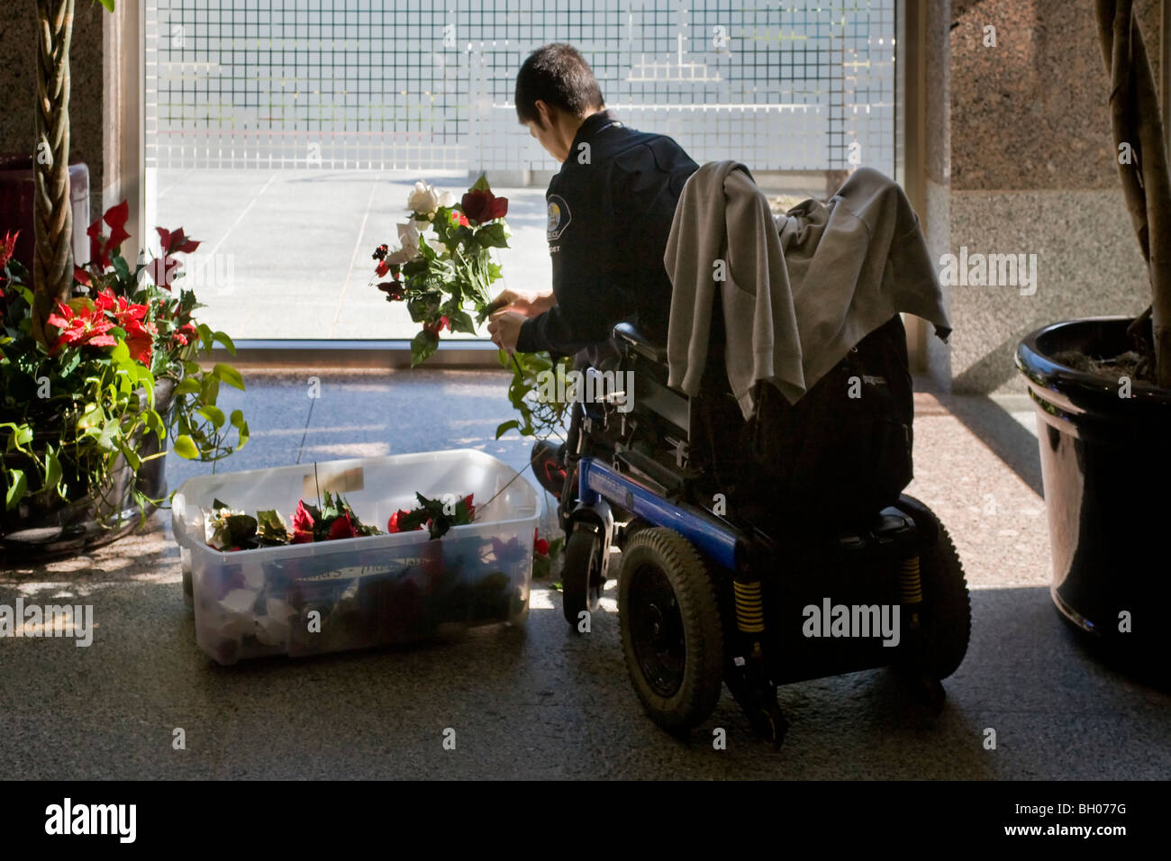Confined to a wheelchair, a handicapped police cadet arranges Christmas flowers at a Southern