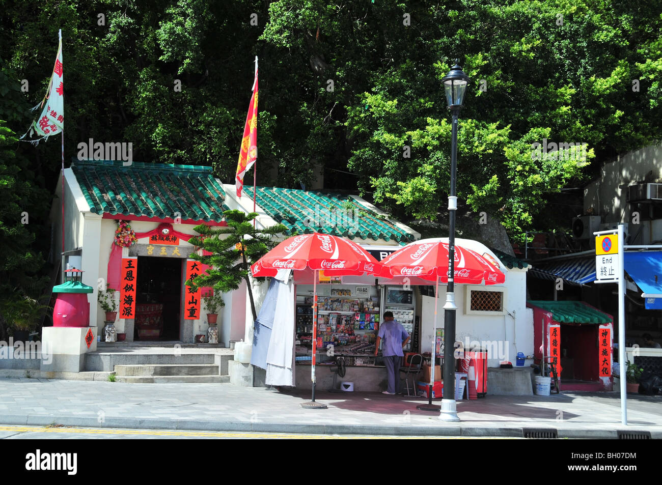 Tai Wong Shrine with prayer flags, next to a shopkeeper selling drinks ...