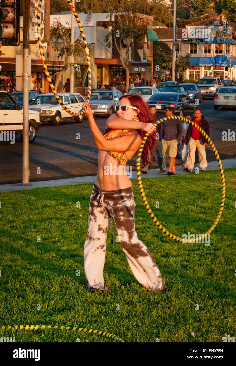 A hula hoop enthusiast holds a 'Hoopnosis' session in late afternoon sun next to Pacific Coast Highway in Laguna Beach, CA Stock Photo