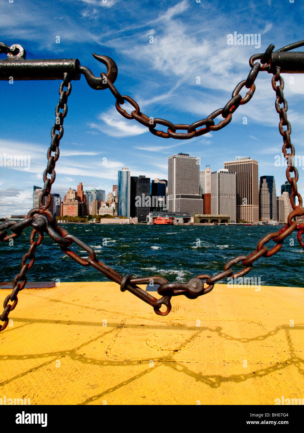 The Lower Manhattan's financial district are seen through the safety chains of the Governor's Island Ferry in New York Harbor. Stock Photo