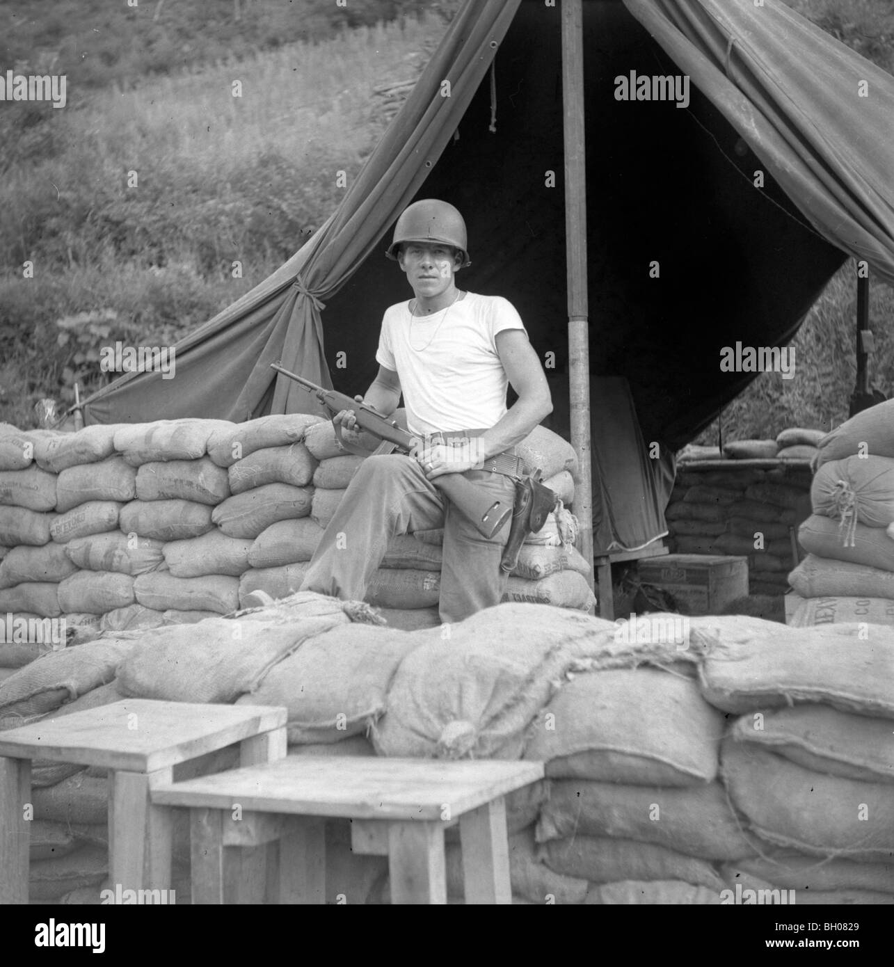 A United States Soldier of the Second Infantry Division holds an M1 rifle while standing next to a tent during the Korean War. Stock Photo