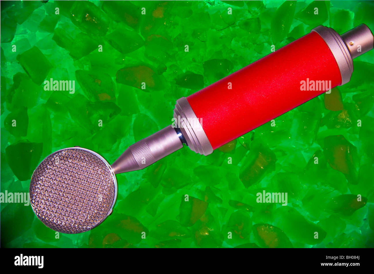 Red microphone sitting on a bed of green ice.  Logos removed to allow for any use. Stock Photo