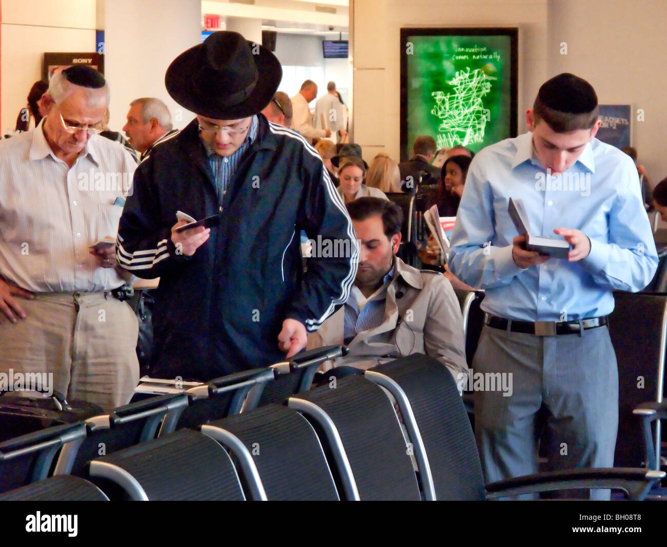 Observant orthodox Jewish men say their evening prayers while waiting to travel at New York City's John F. Kennedy Airport. Stock Photo