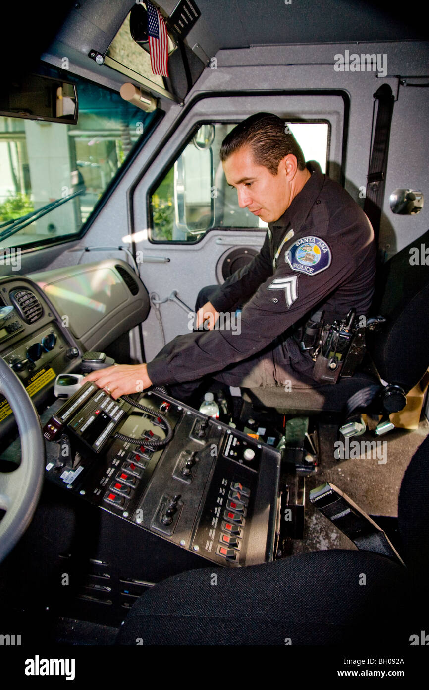 A SWAT (Special Weapons And Tactics) team police officer examines the cab control console of an armored assault vehicle. Stock Photo