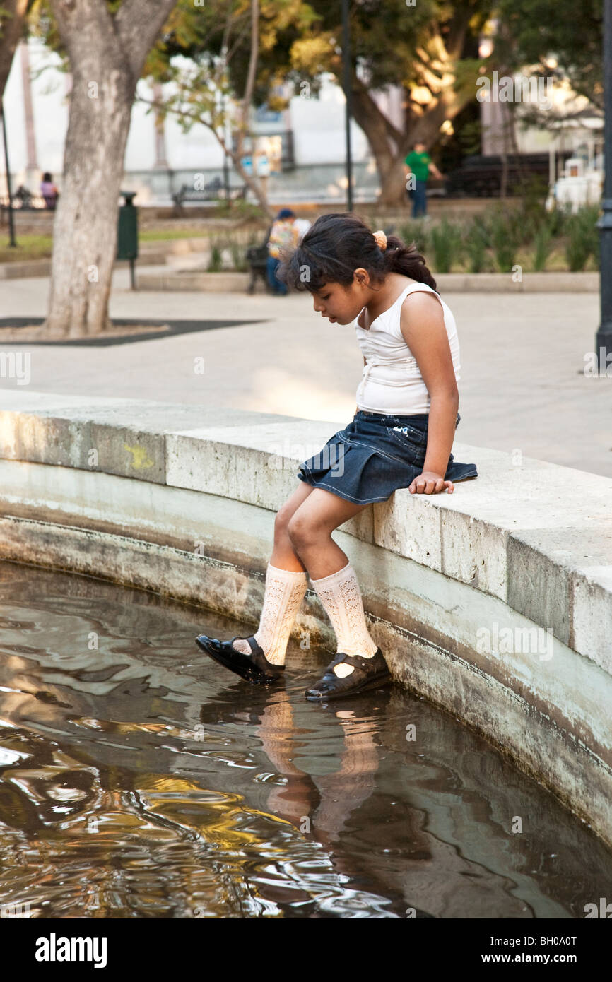 small Mexican girl sits on rim of Juarez Park fountain & experiments with  the thrill of getting her shoes wet Oaxaca City Mexico Stock Photo - Alamy