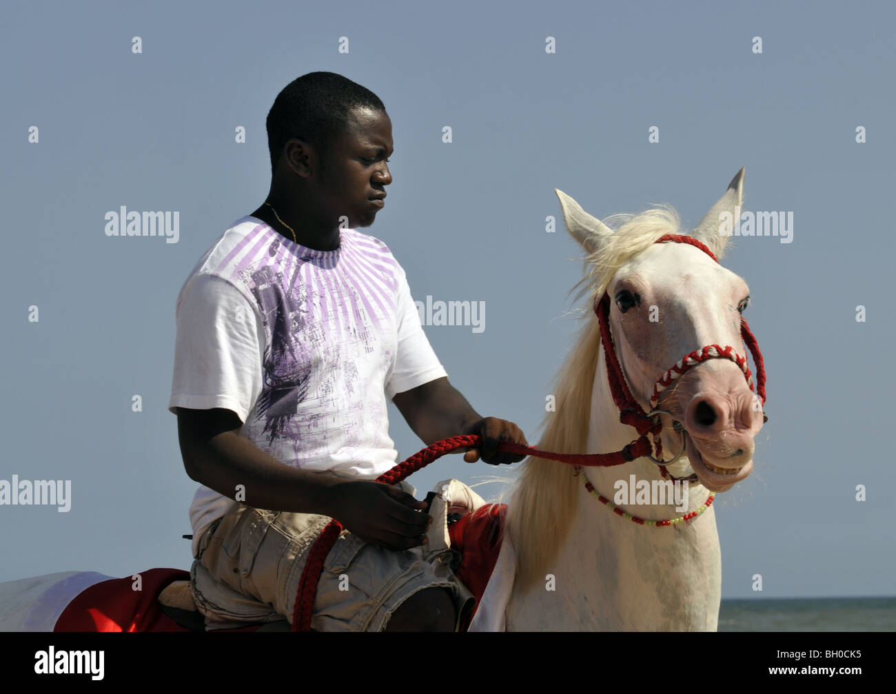 A man rides a horse on a beach in Ghana Stock Photo