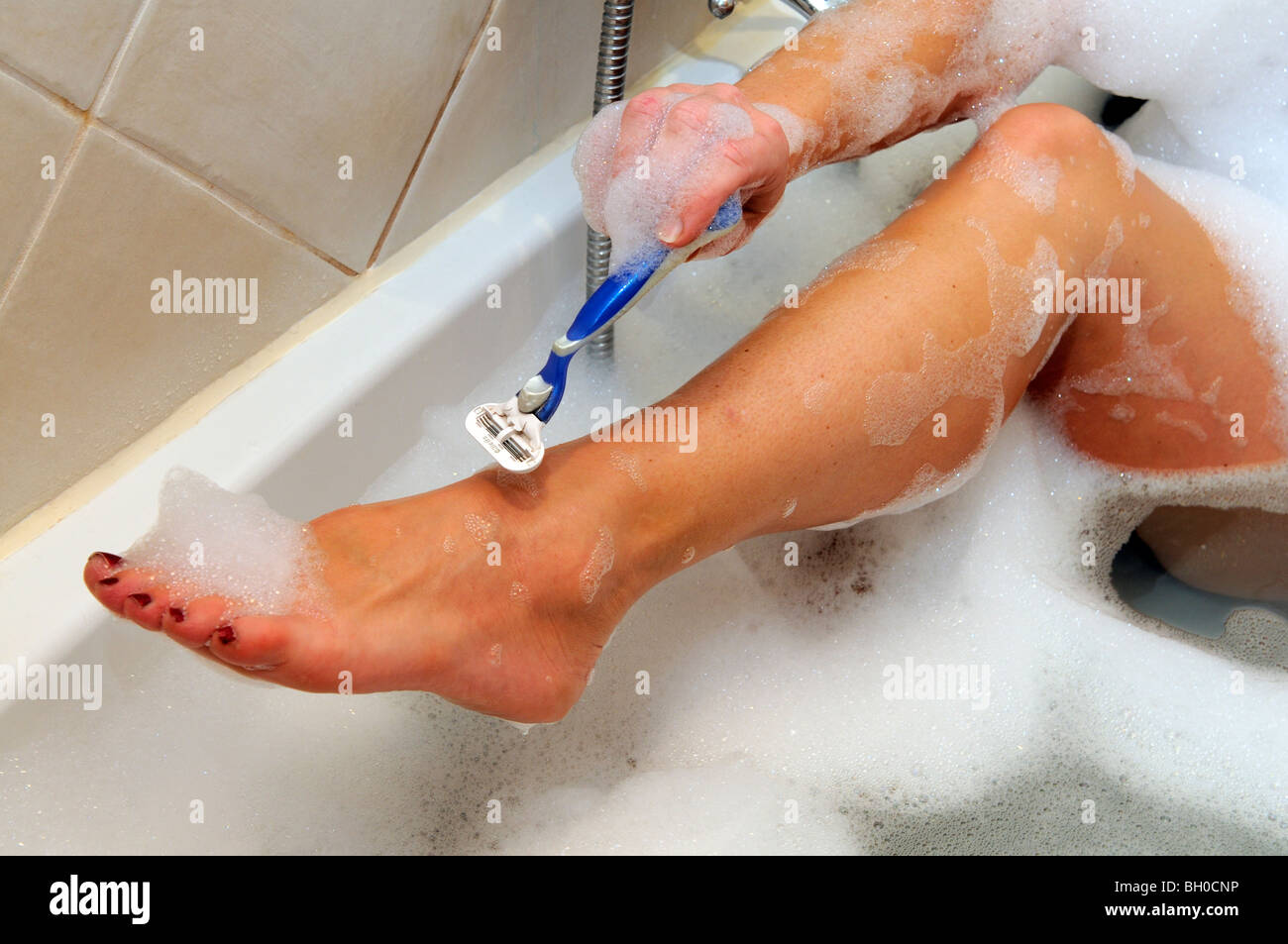Woman using a Gillette safety razor to shave her legs Stock Photo