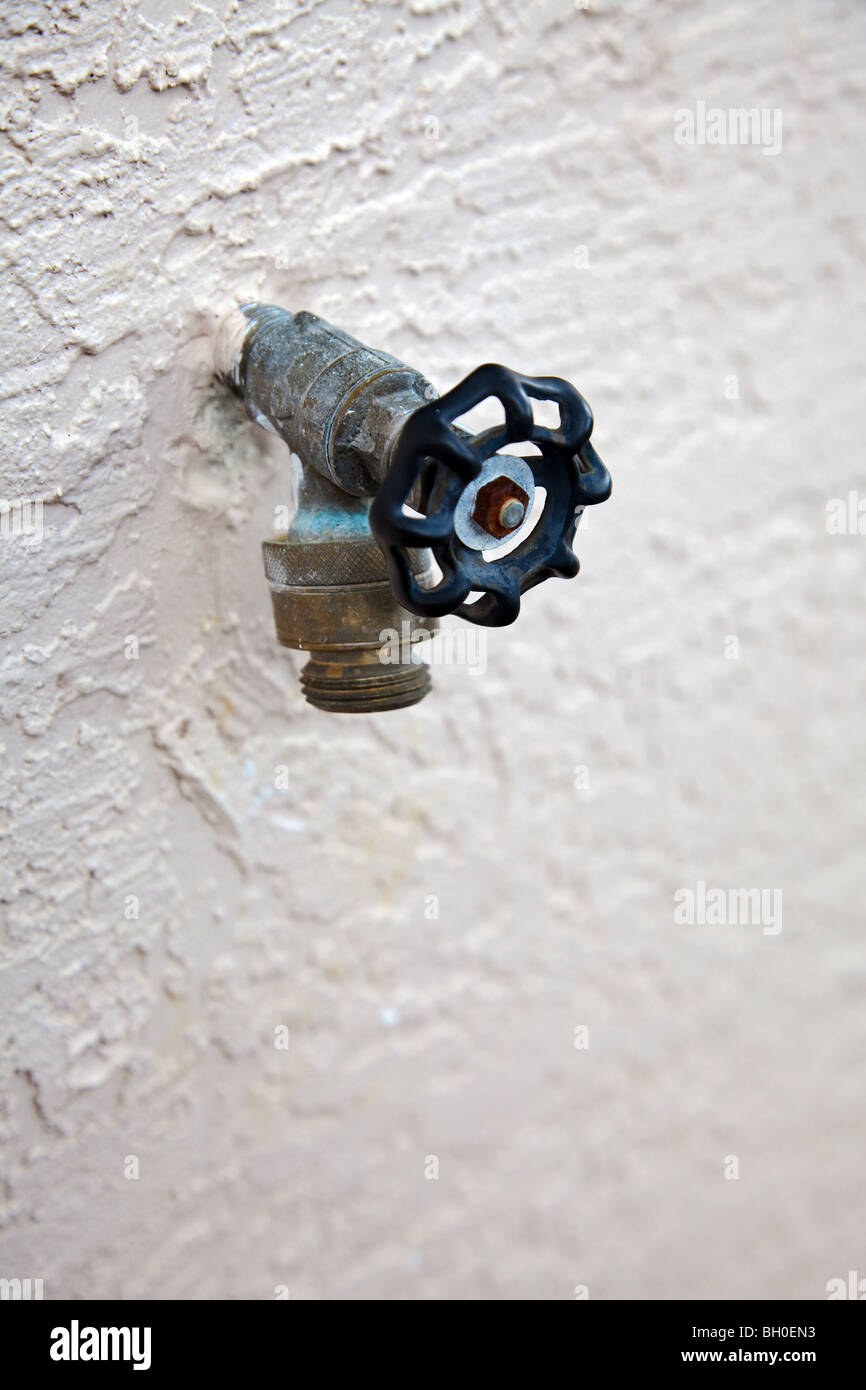 water spigot with backflow preventer valve on stucco wall Stock Photo