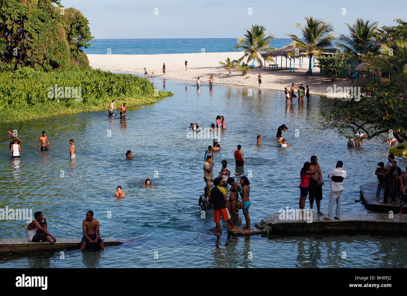 People swimming in a fresh water river flowing into the Caribbean Sea, Playa San Rafael, Dominican Republic Stock Photo