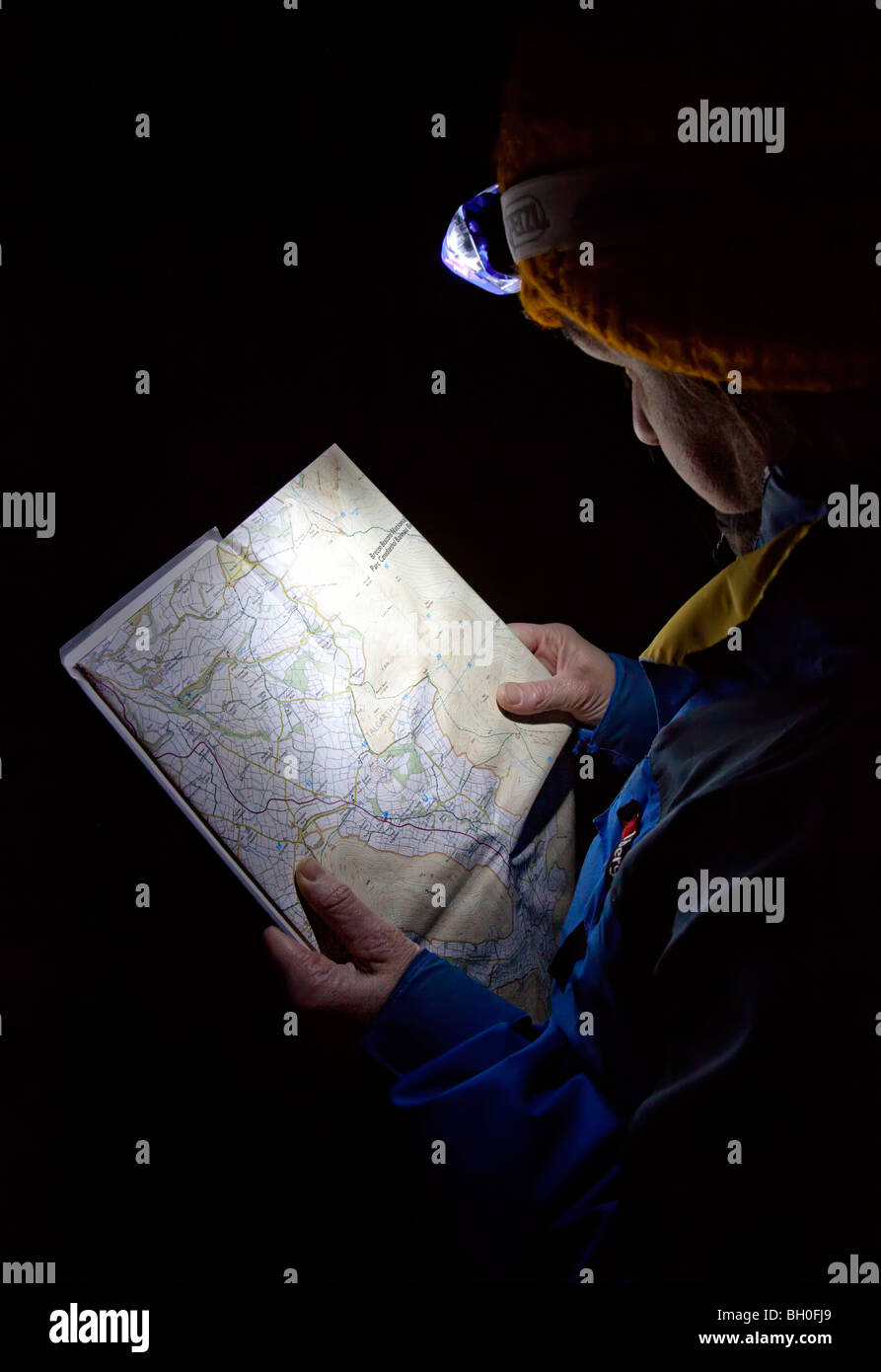 Woman walker using headlight to read a map at night UK Stock Photo
