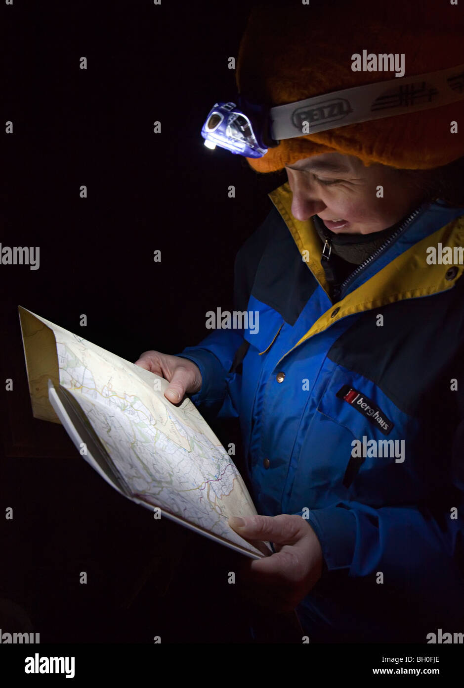 Woman walker using headlight to read a map at night UK Stock Photo