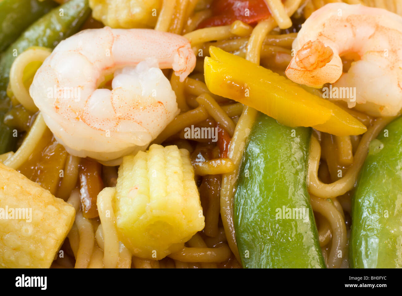 macro view of shrimp stir fry noodles with snap peas, and baby corn
