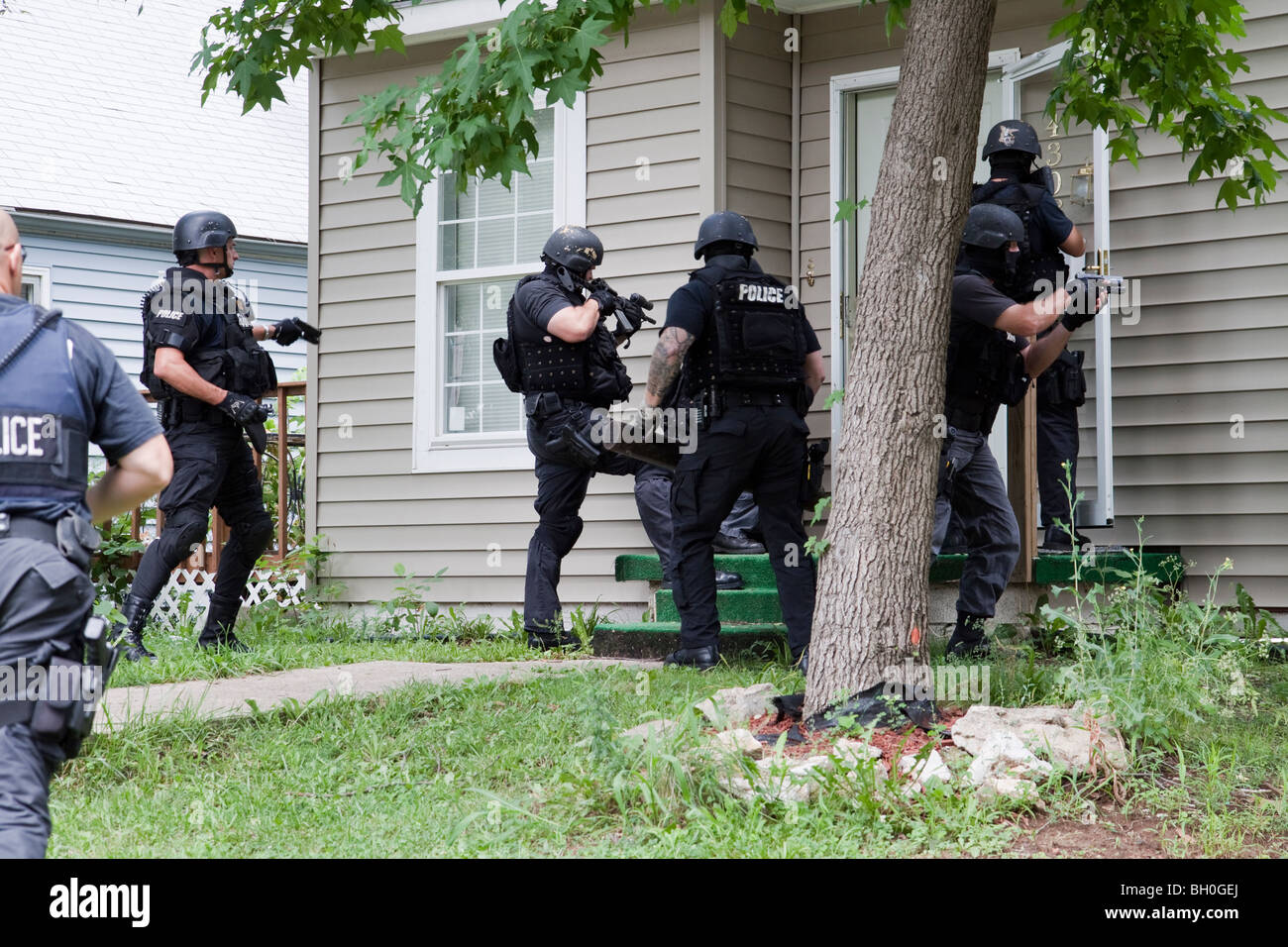 Police from tactical team making entry to serve a high-risk drug related search warrant. Street Narcotics Unit. Stock Photo