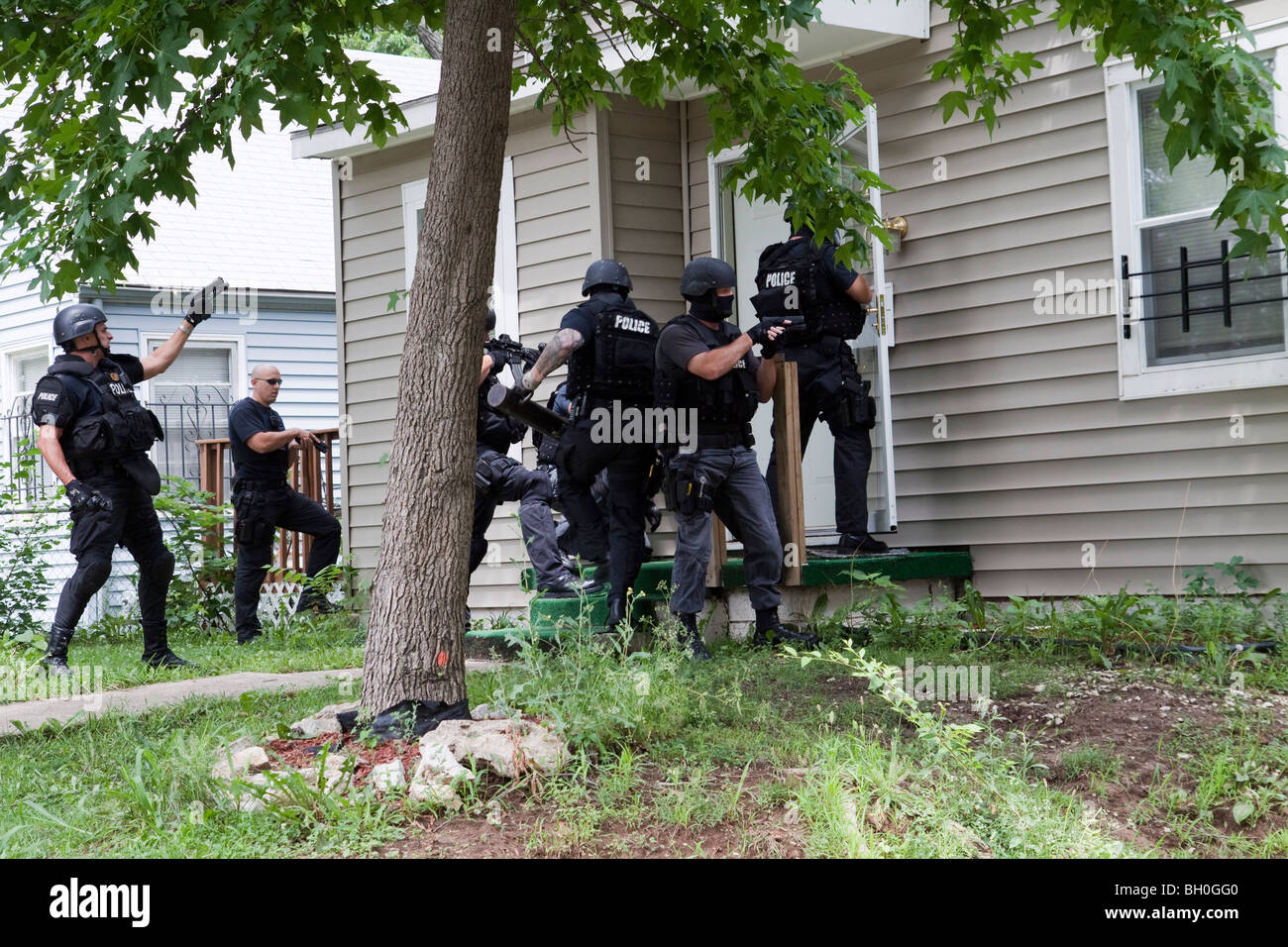 Police from tactical team making entry to serve a high-risk drug related search warrant. Street Narcotics Unit. Stock Photo