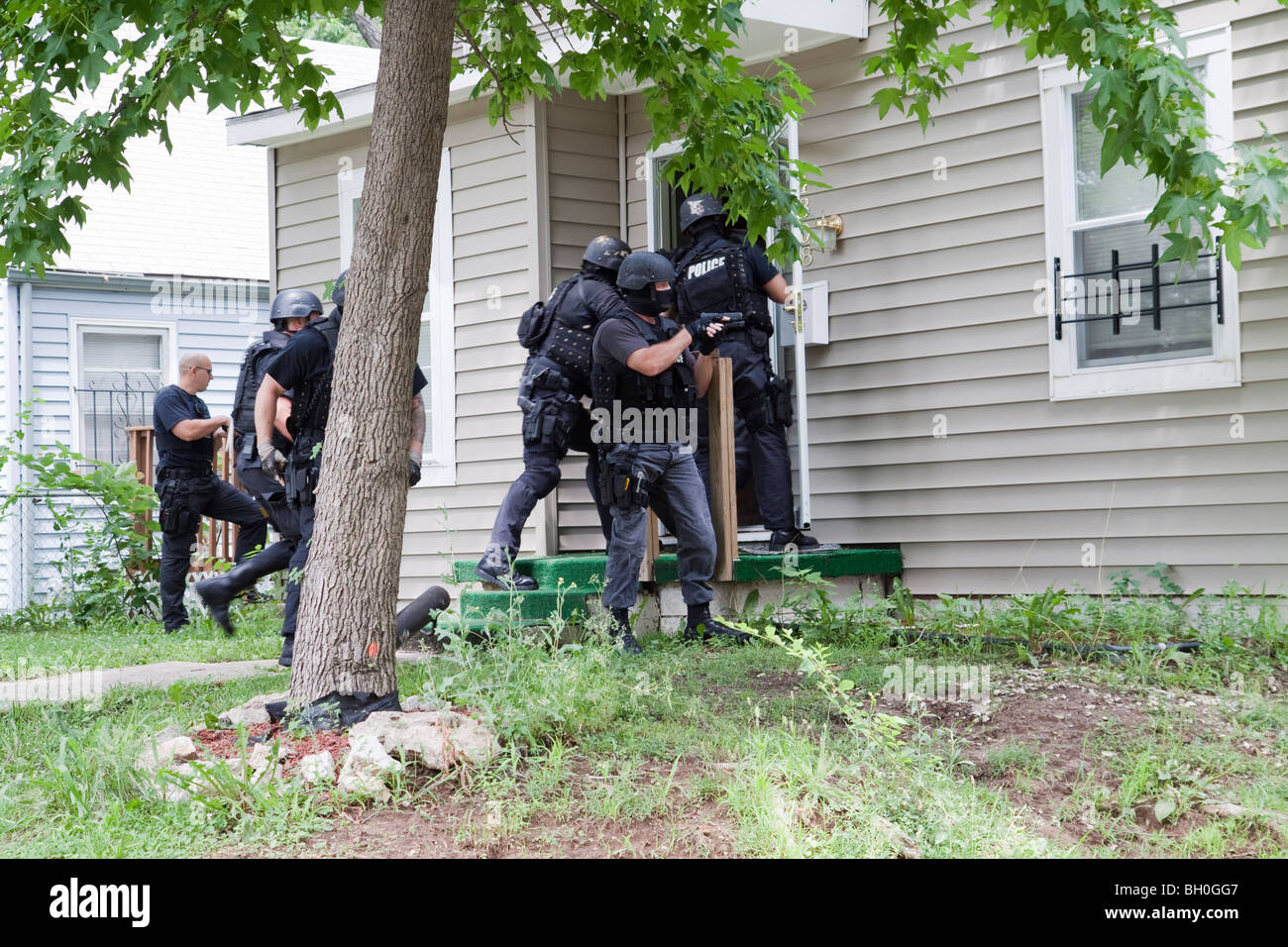 Police from tactical team making entry to serve a high-risk drug related search warrant. Street Narcotics Unit. Stock Photo