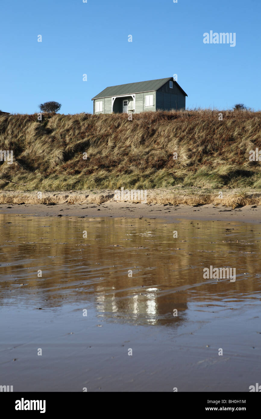 Beach hut reflected in wet sand at Low Newton by the Sea in Northumberland, England, UK Stock