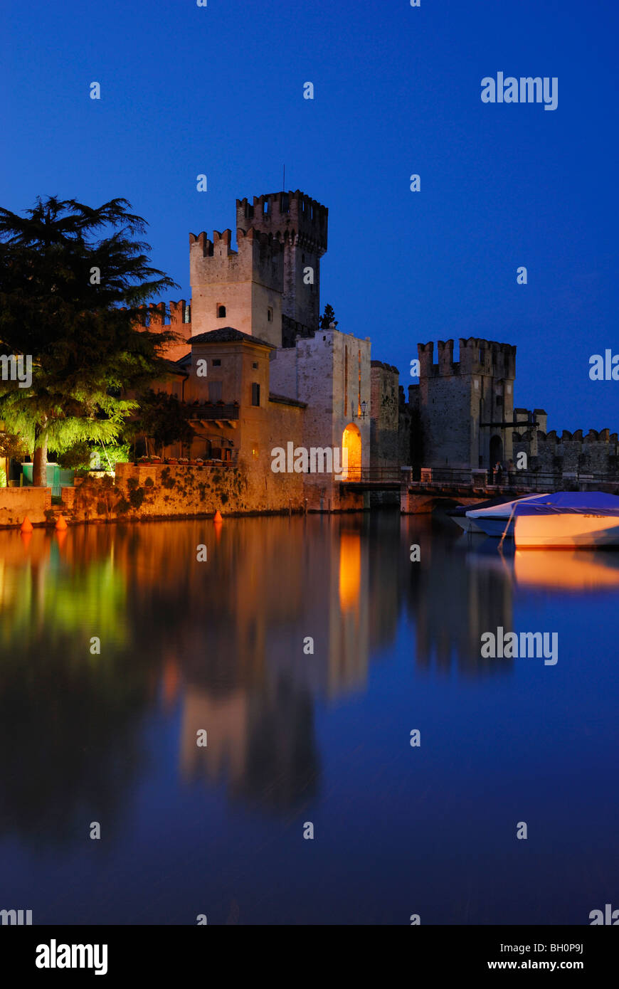 Reflection of illuminated Castello Scaligero in lake Garda, Sirmione ...